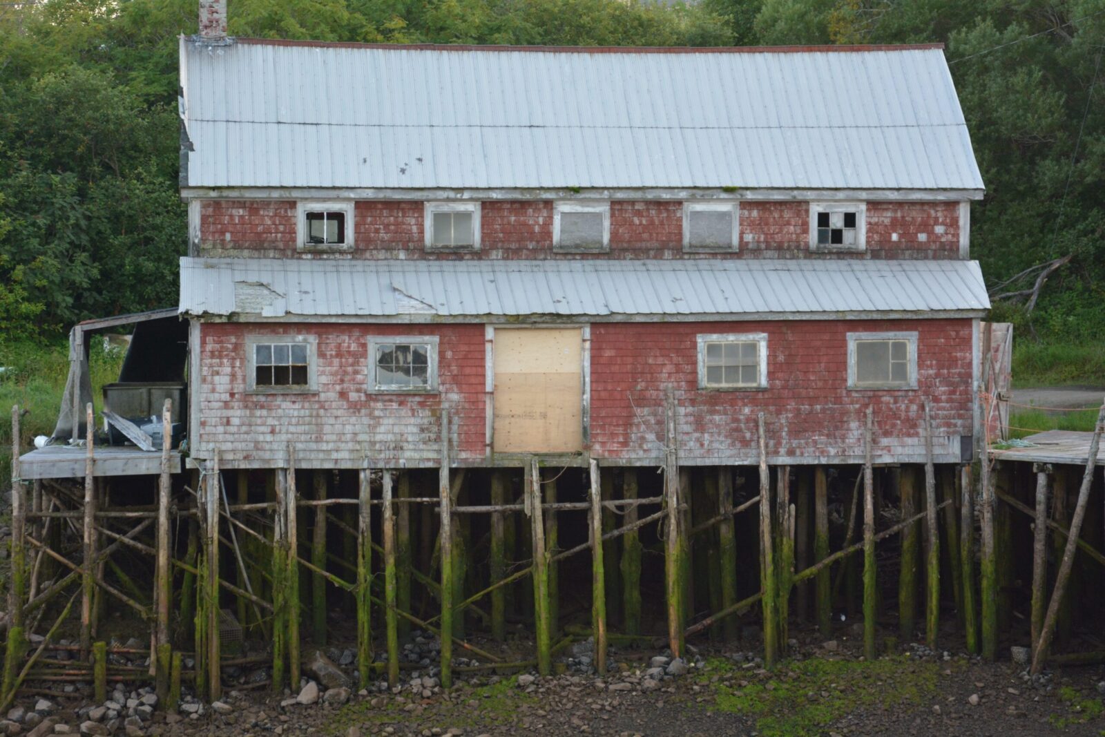 An old red building sits on top of a wooden pier.