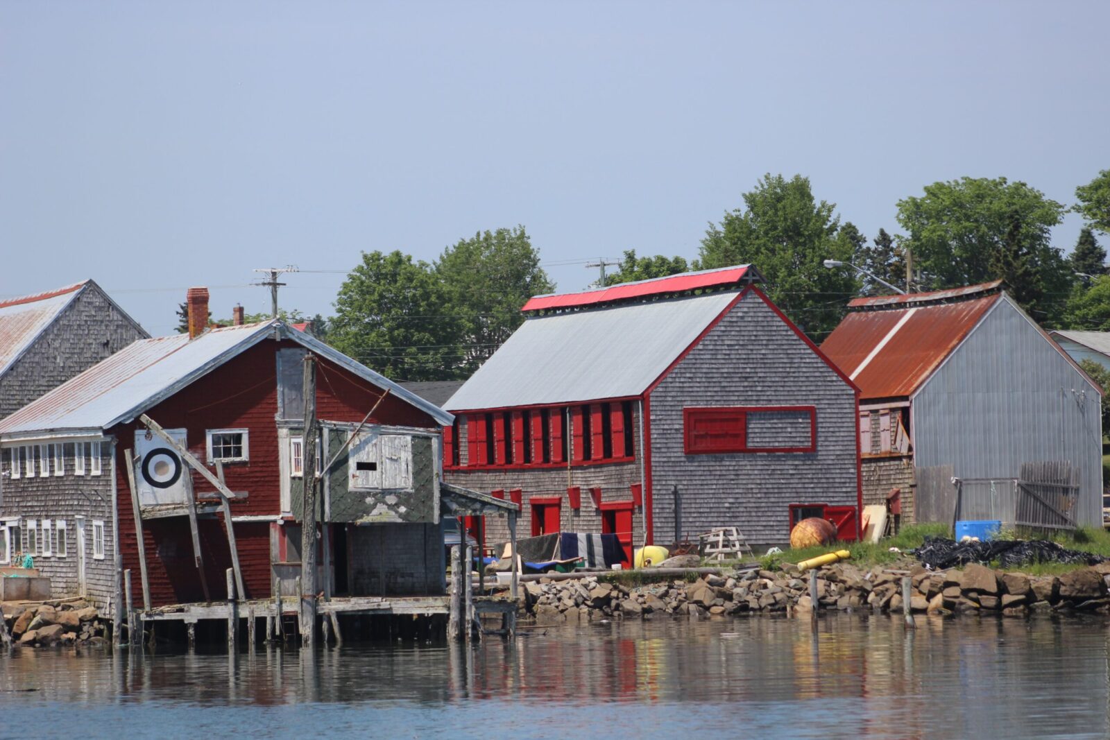 A row of red houses next to a body of water.