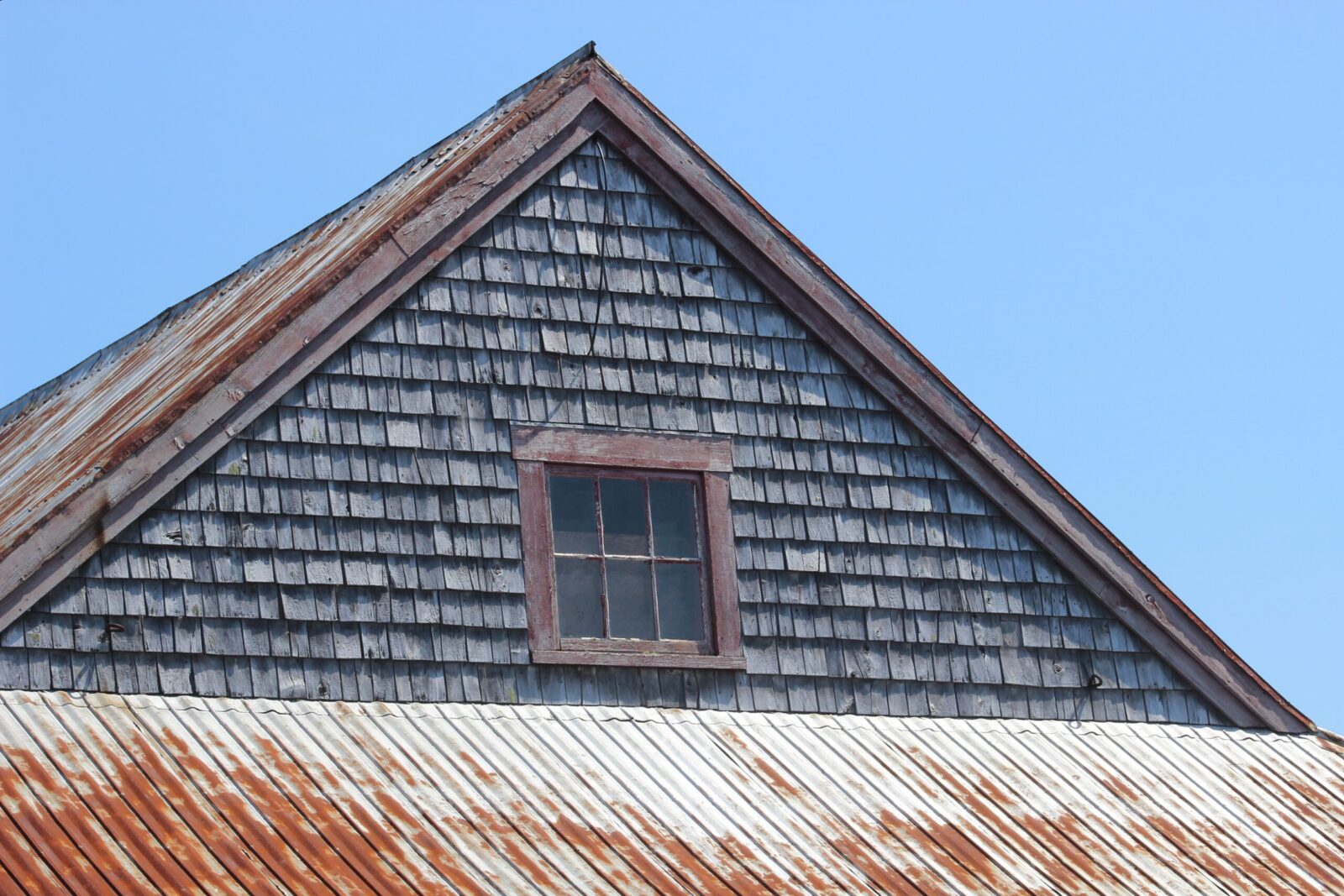A rusty tin roof with a window.
