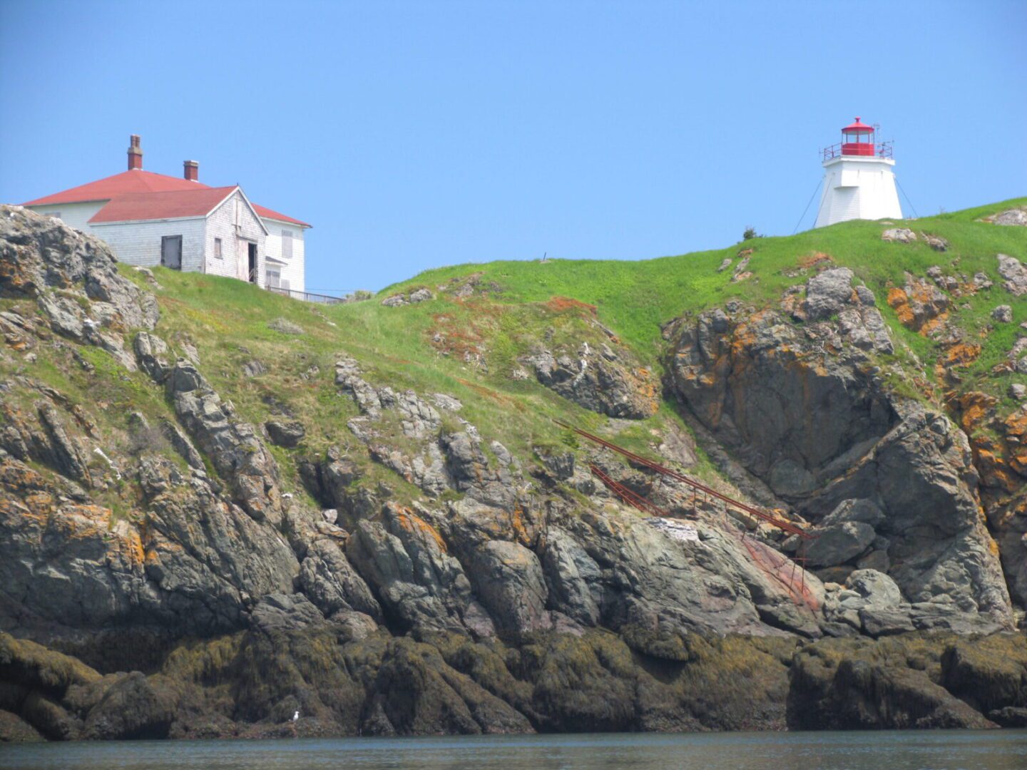 A lighthouse sits on top of a rocky hill.