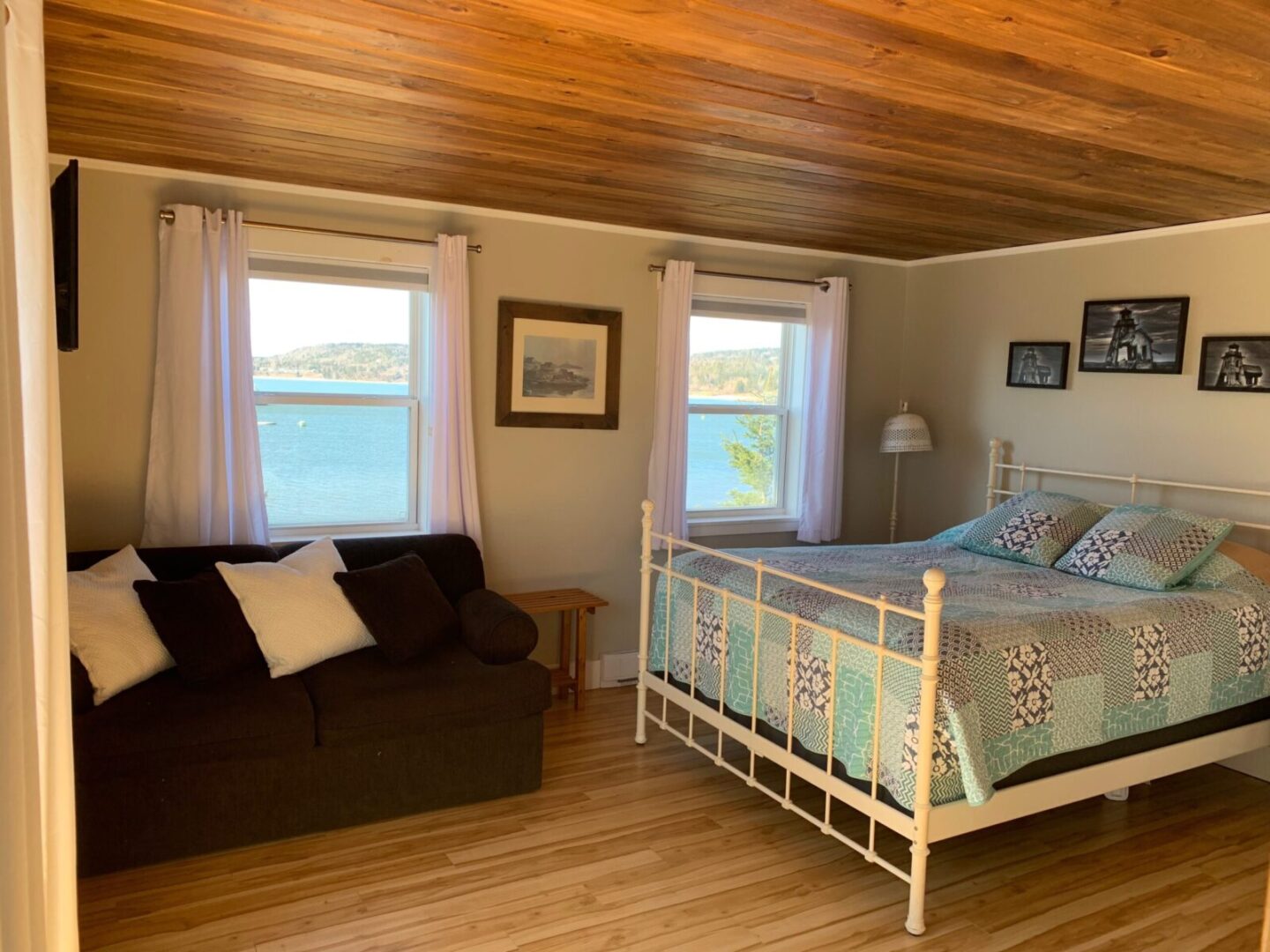 A bedroom with hardwood floors and a view of the ocean.