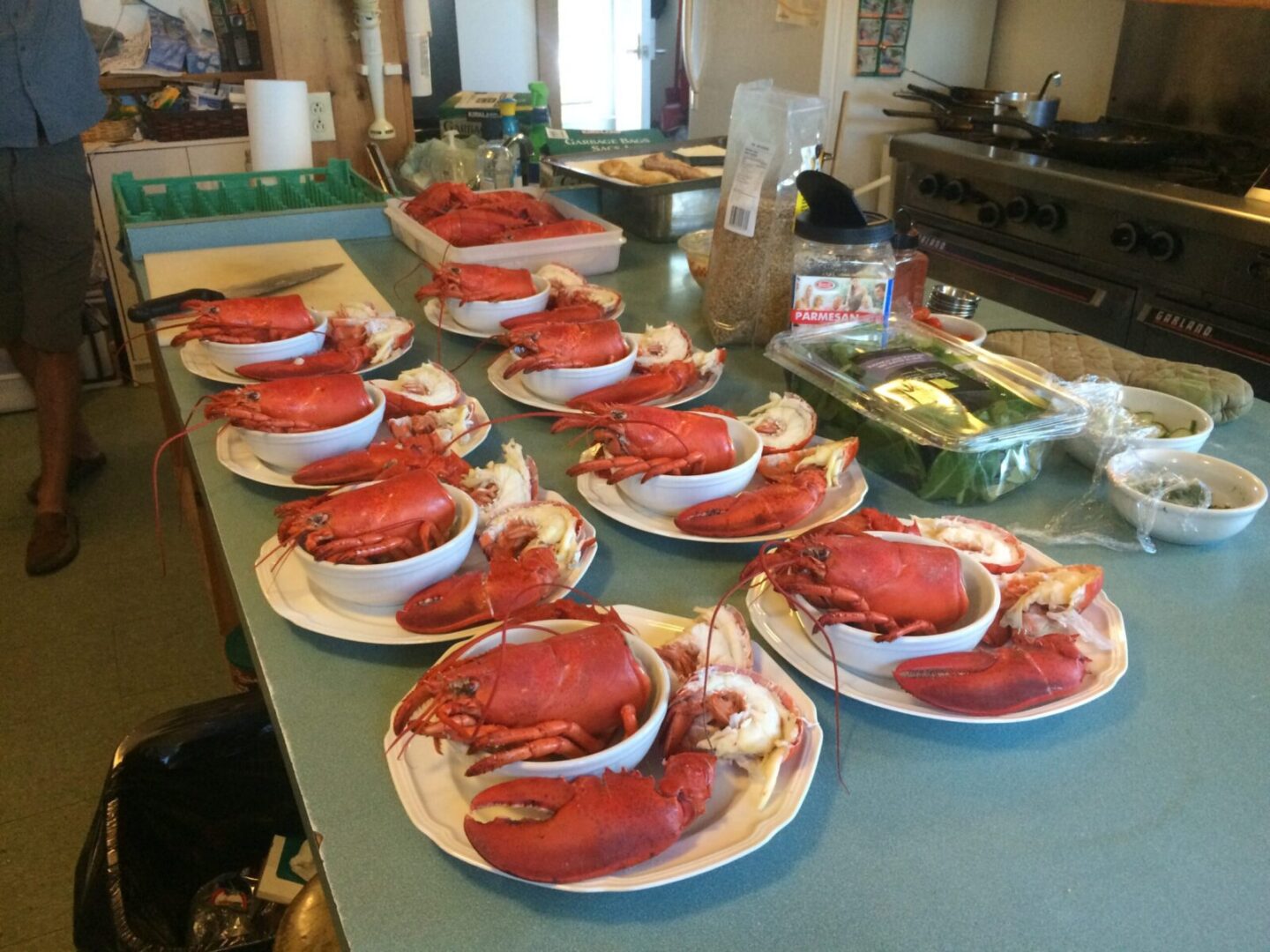 A kitchen with a table full of plates of lobsters.