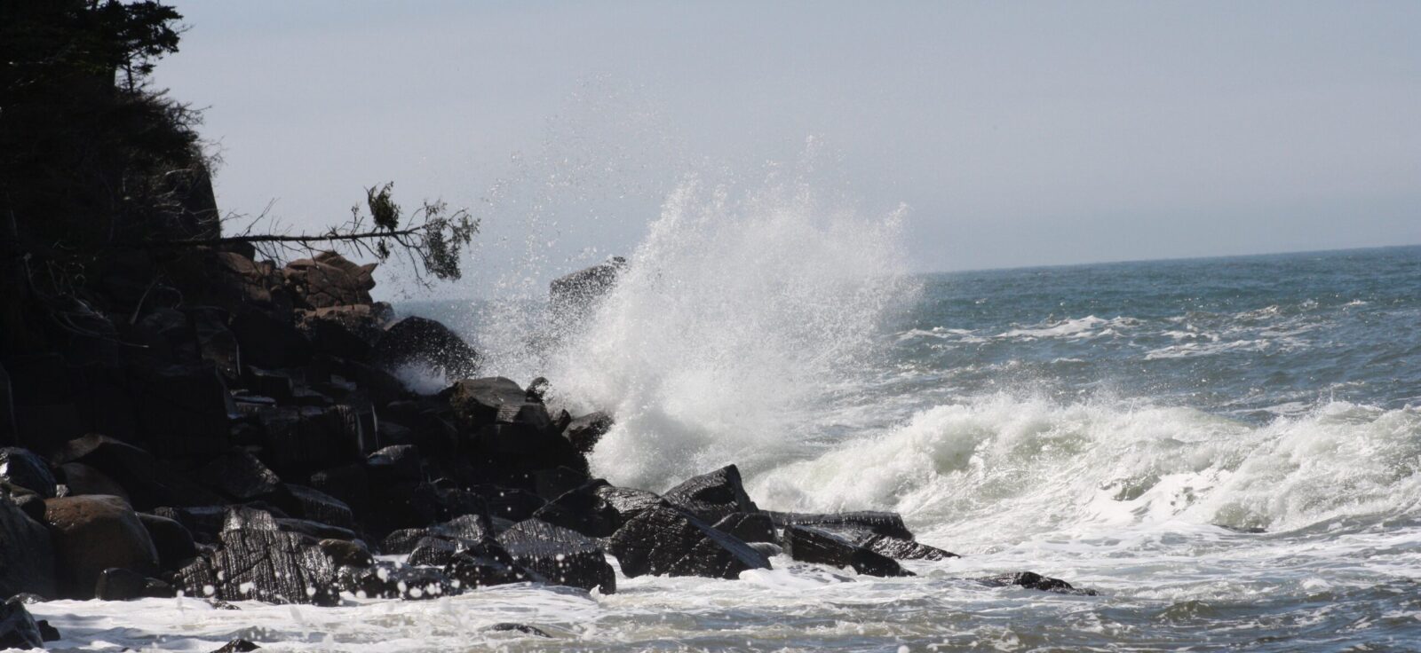 A large wave crashing into a rocky shore.
