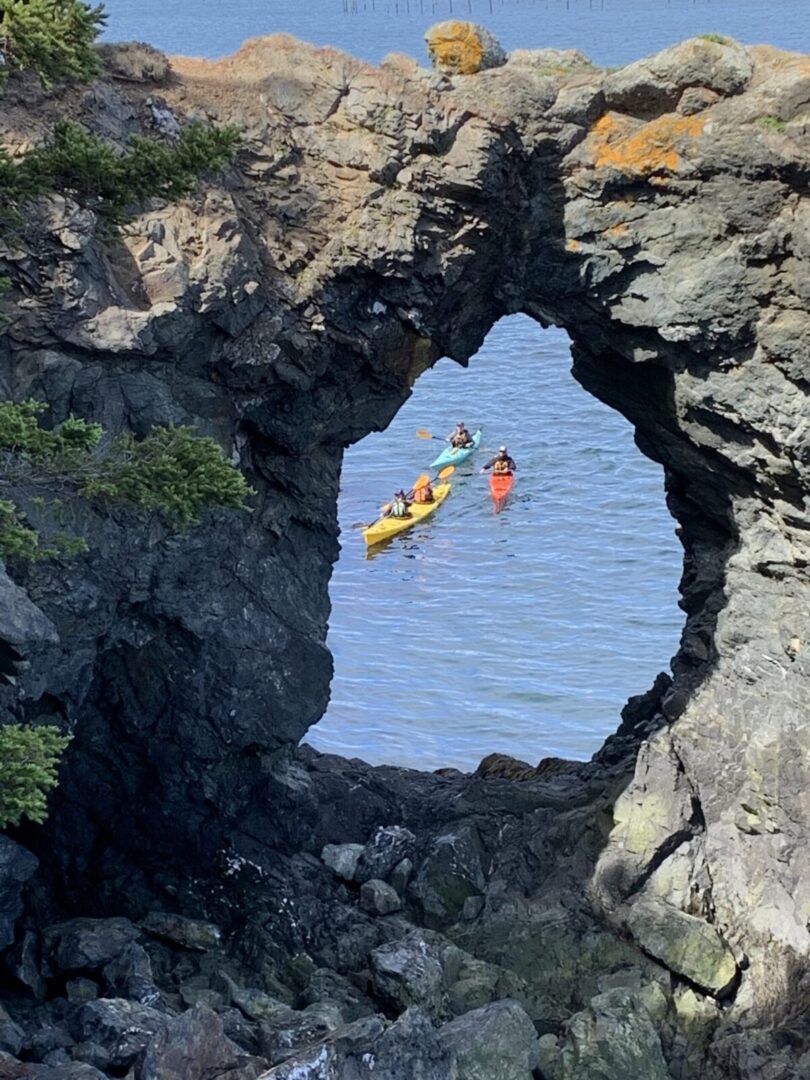 Two people kayaking through a rock arch.