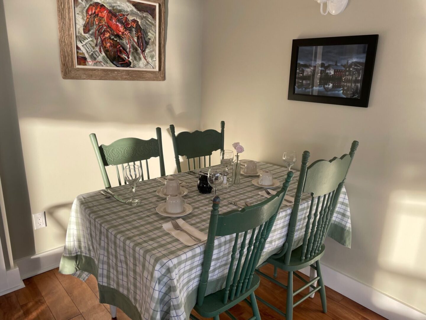 A dining room table with green chairs and a picture.