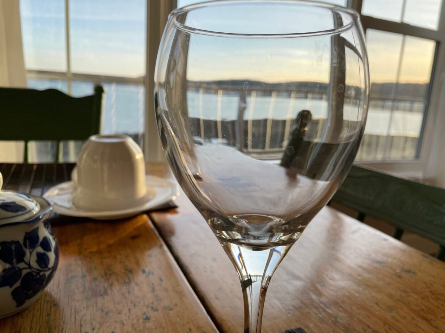 A wine glass on a table with a view of the ocean.