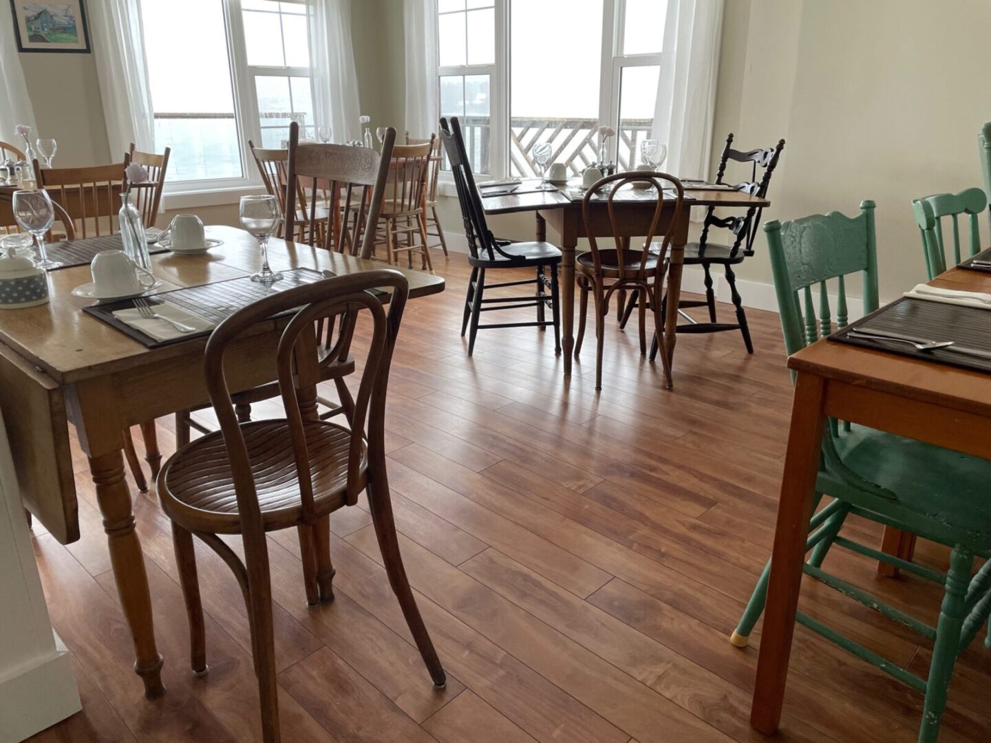 A dining room with tables and chairs on a wooden floor.
