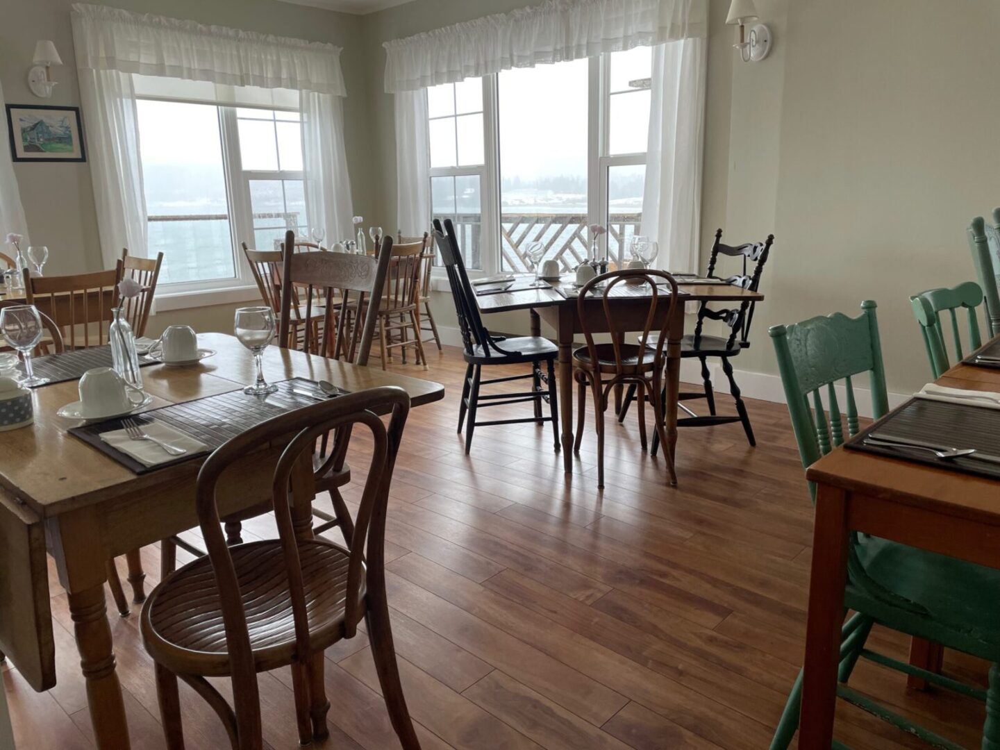 A dining room with wooden tables and chairs and a view of the ocean.