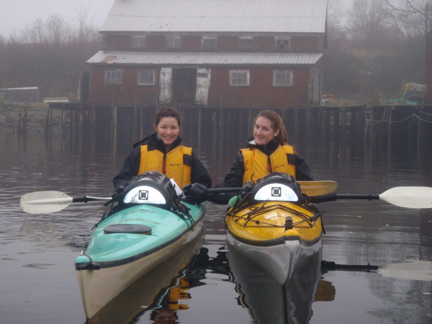 Two women in kayaks on a body of water.