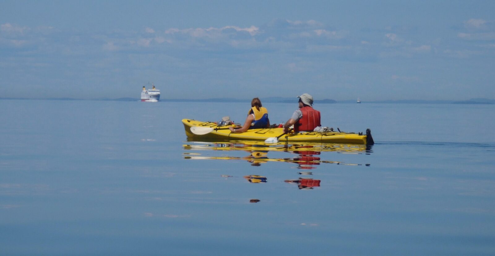 Two people paddling in a yellow kayak on the water.