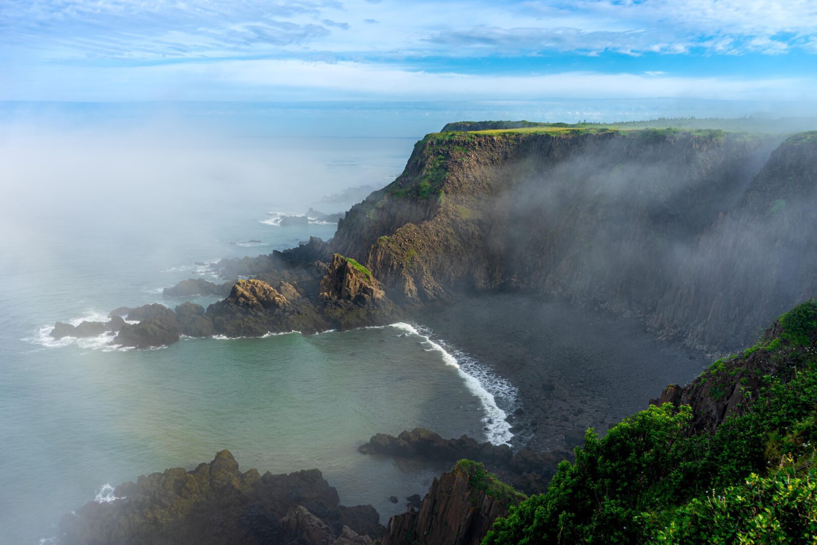 A cliff overlooking the ocean and fog.