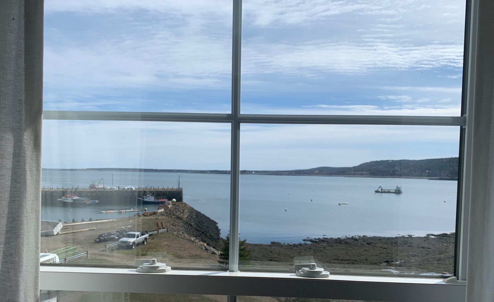 A window with a view of a harbor and a boat.