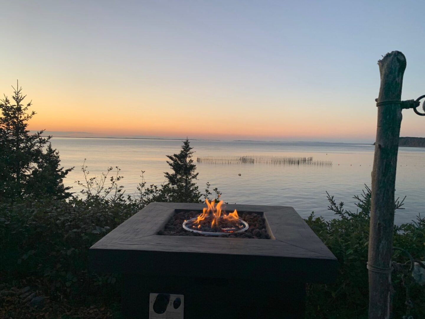 A fire pit in front of a body of water.