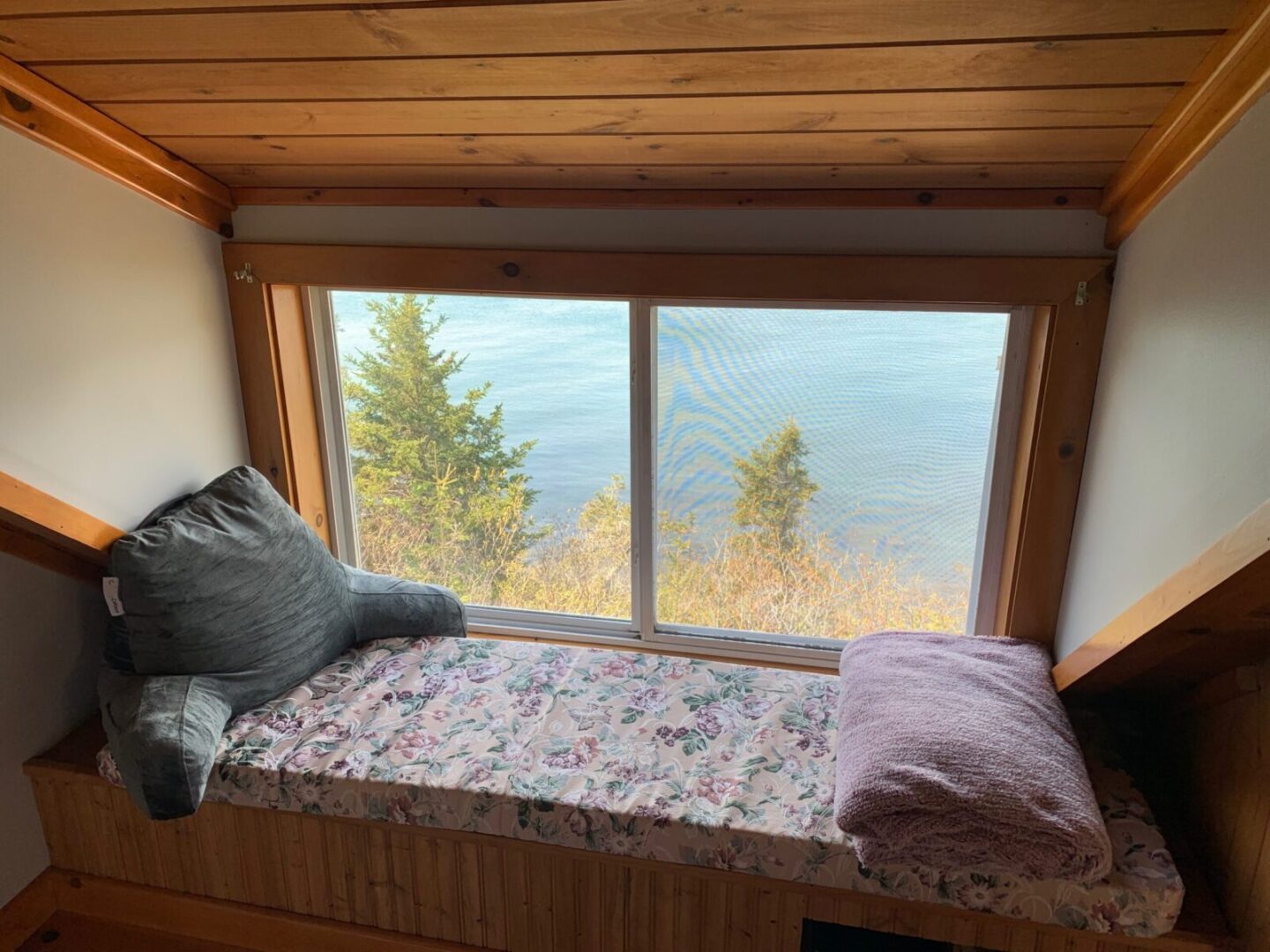 A window seat in a room with a view of the ocean.