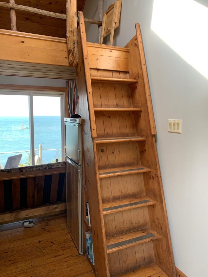 A wooden staircase leading to a room with a view of the ocean.
