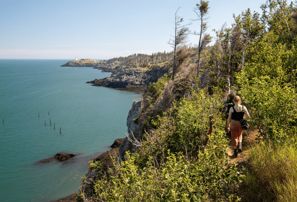 A person hiking along a rocky path near a body of water.