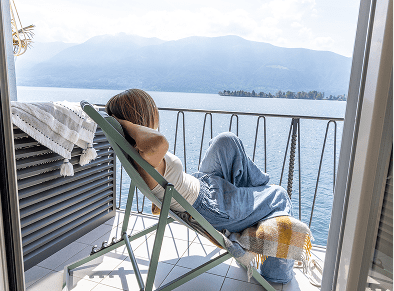 Person relaxing on balcony overlooking lake.