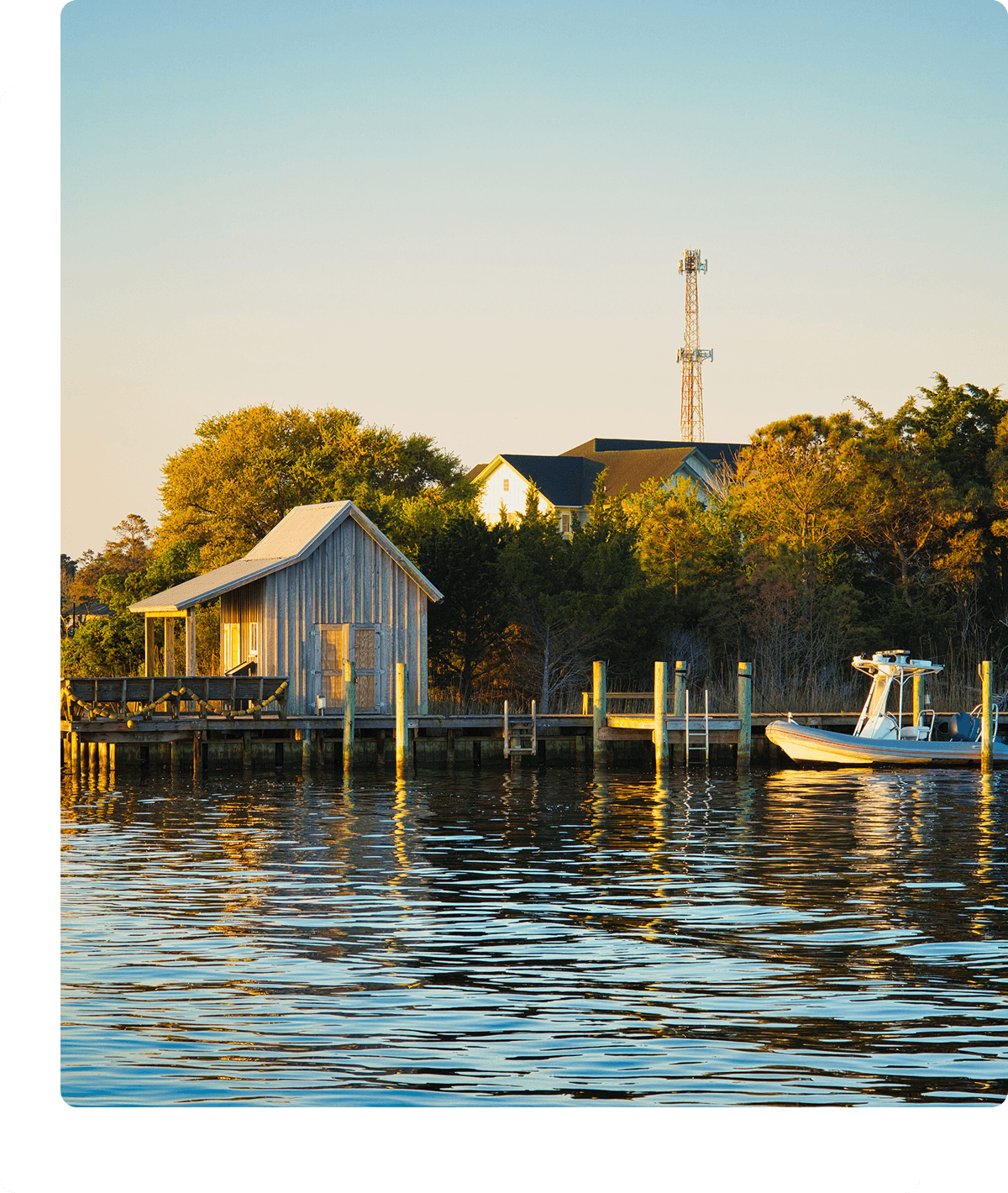Boat docked by lakeside cabin at sunset.