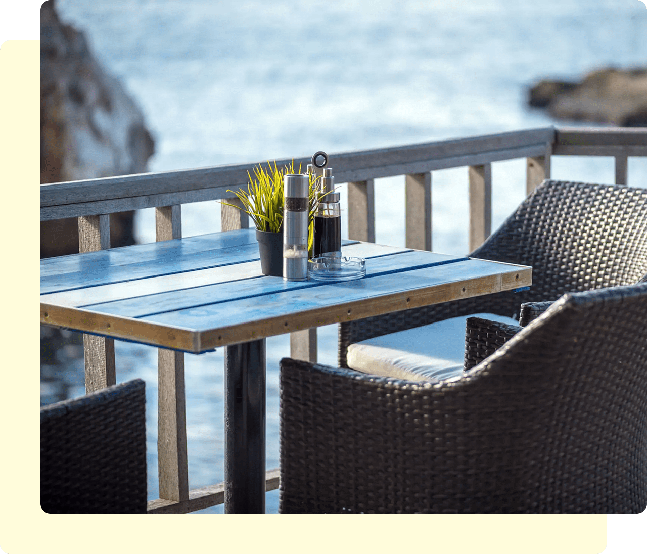 Oceanfront dining table with chairs and condiments.