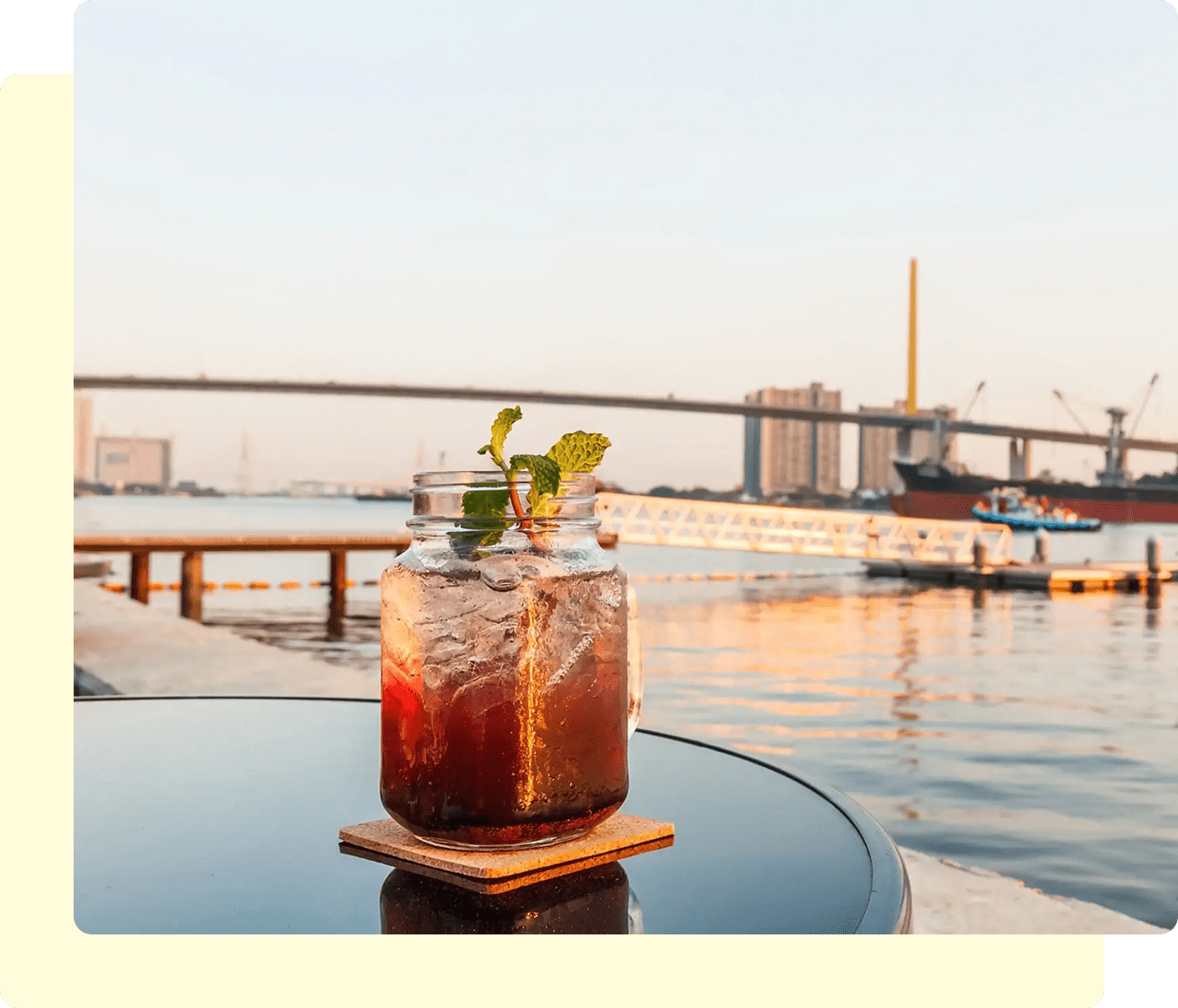 Iced drink by riverside with bridge background.