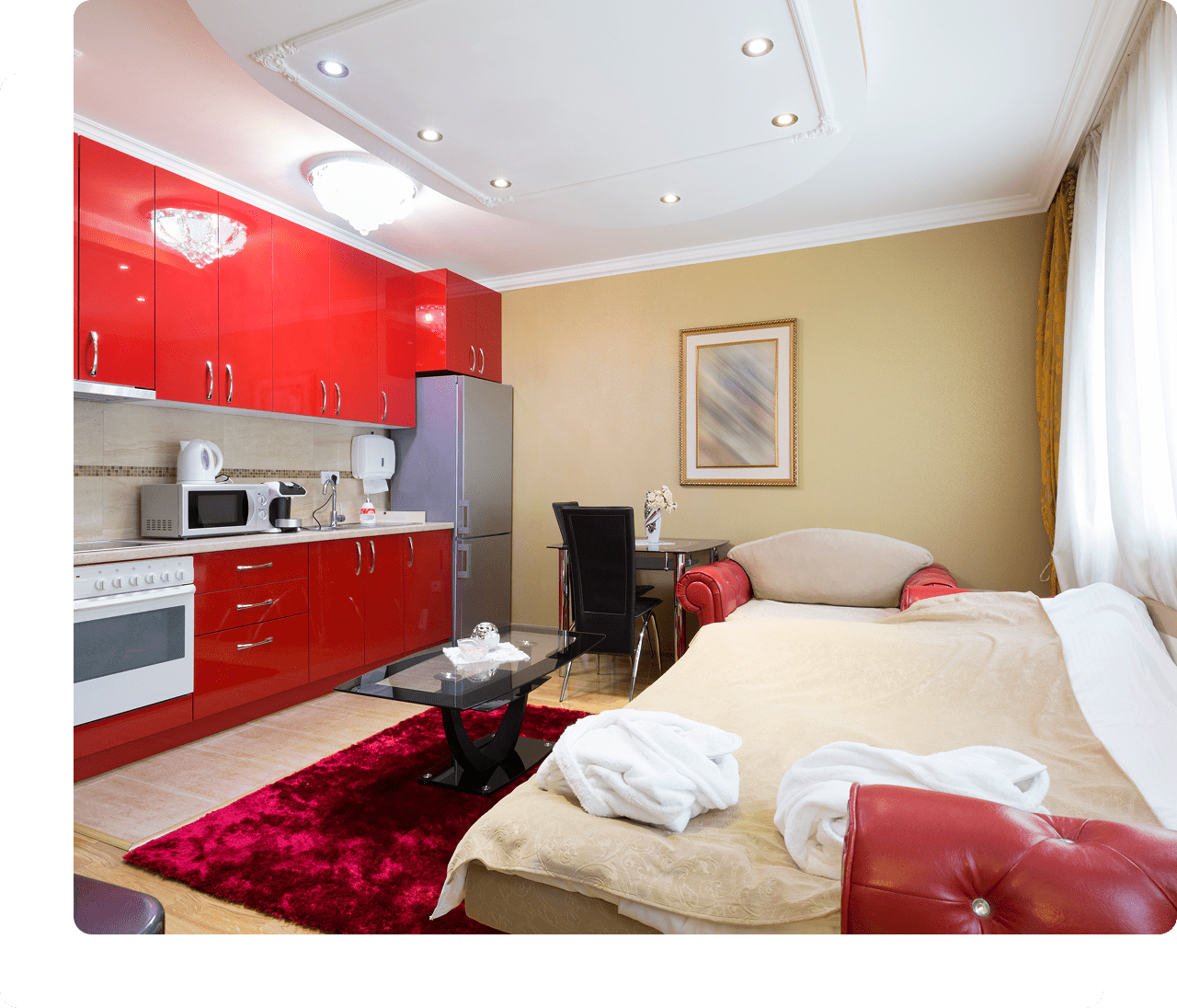 Modern studio apartment with red kitchen cabinets.
