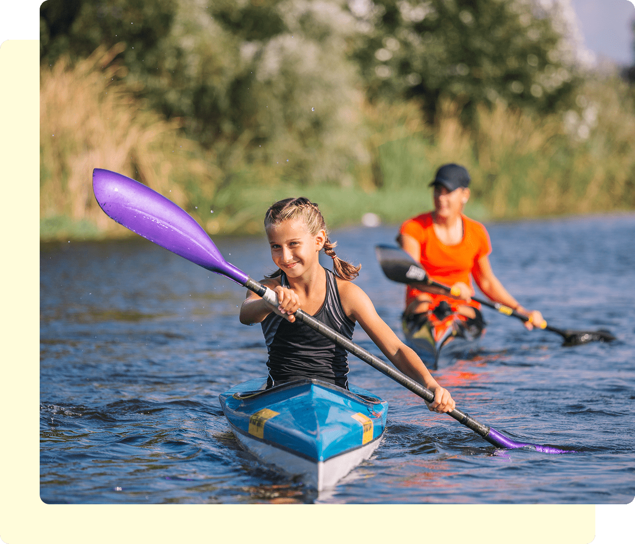 Girl kayaking with woman on river.