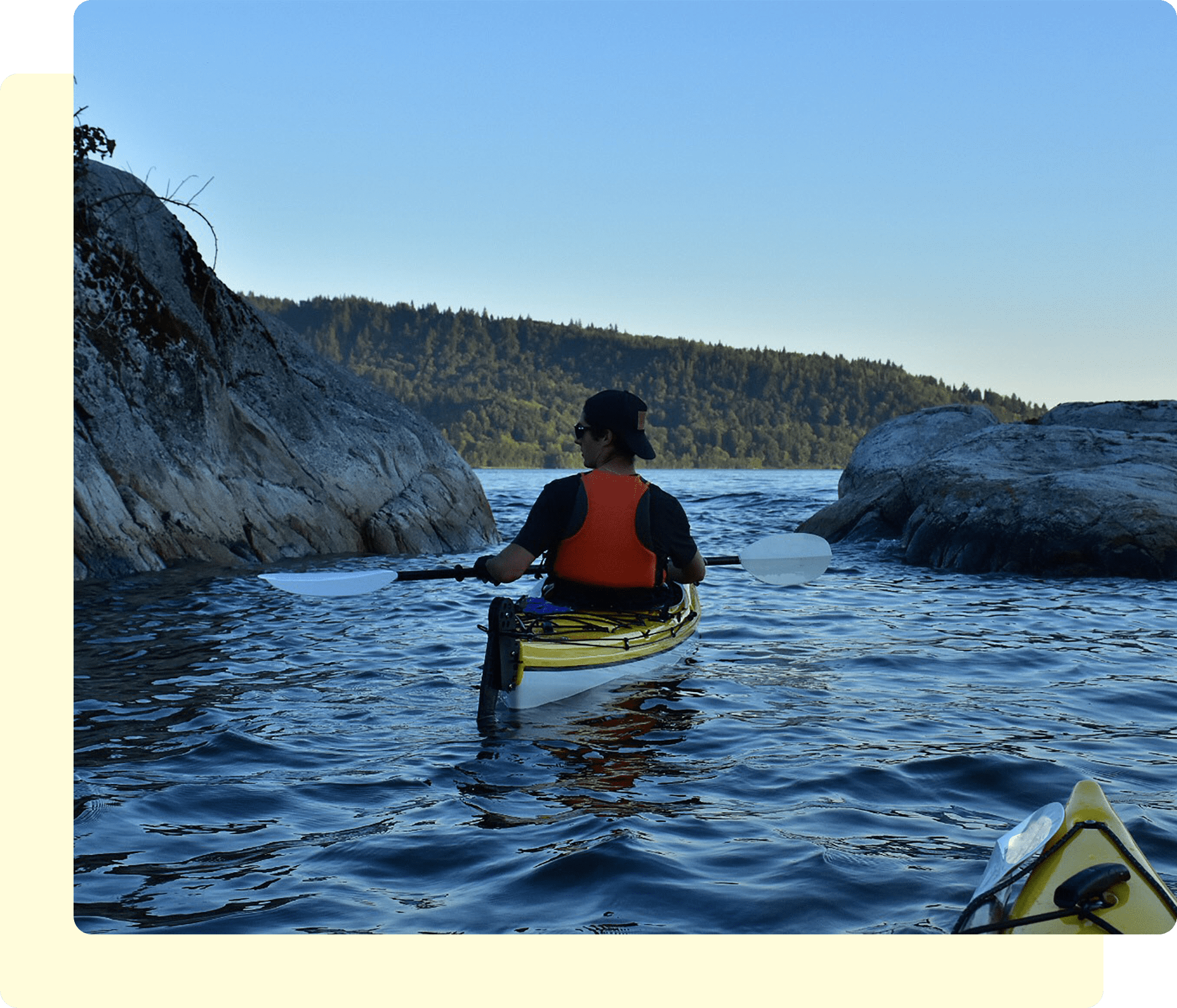 Person kayaking between rocks on calm water.