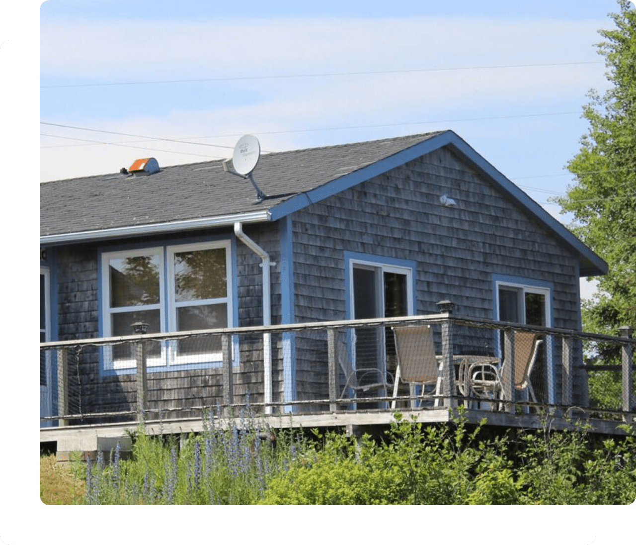 Wooden cabin with deck and satellite dish.