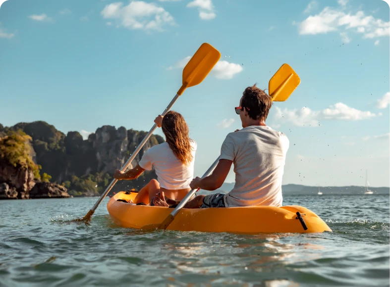 Couple kayaking on scenic, sunny lake.