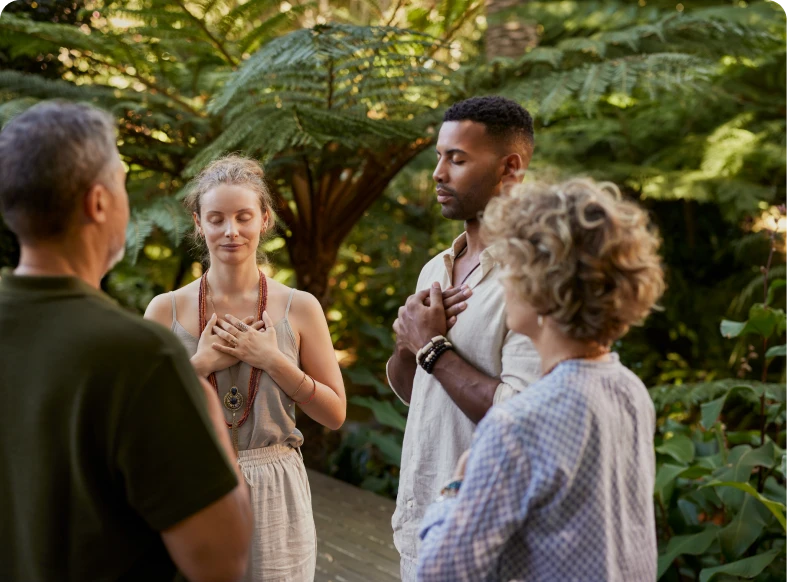 Group meditating outdoors in a lush garden.