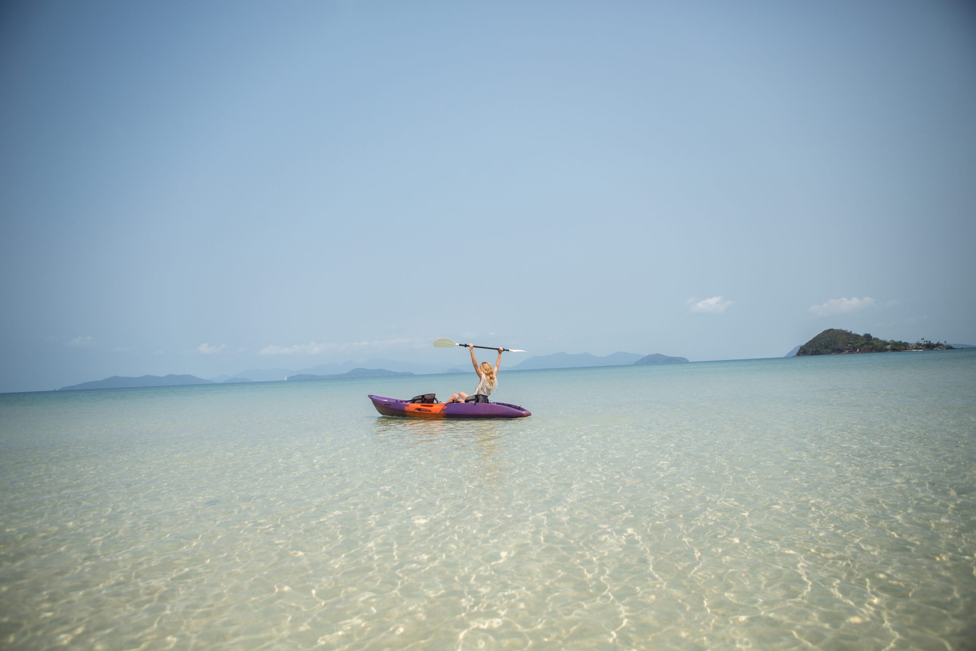 Person kayaking on clear turquoise water.