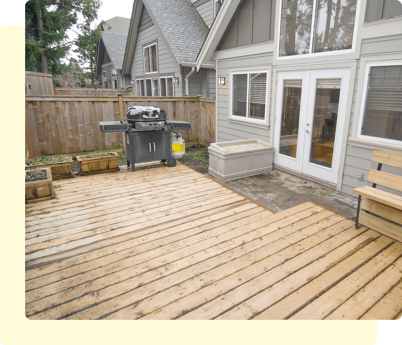 Wooden patio with grill and bench.