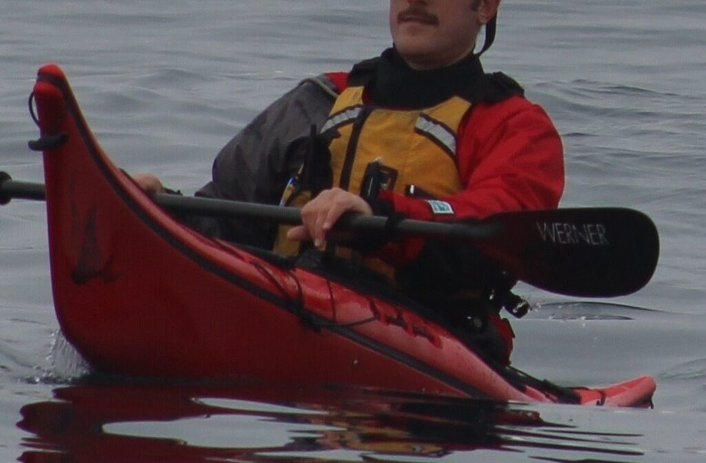 Person kayaking on calm water surface.