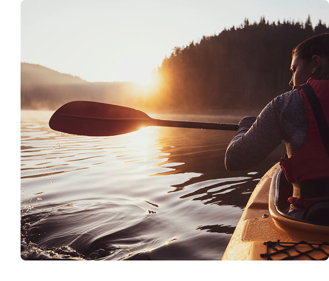 Person kayaking on a lake at sunset.