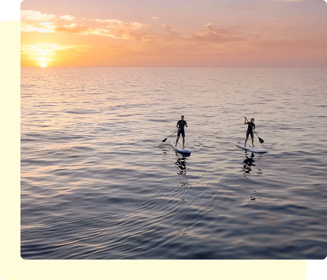 Paddleboarding at sunset on calm ocean.