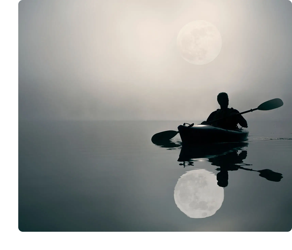 Kayaker on serene lake under full moon.
