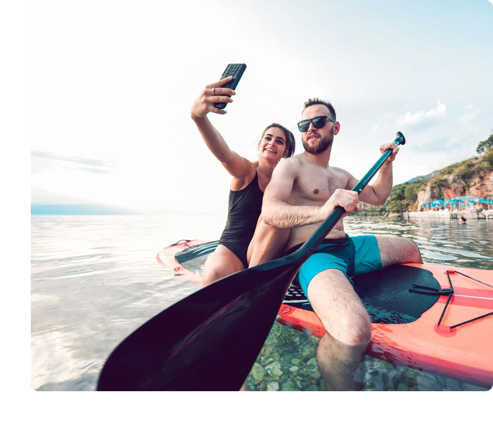 Couple taking selfie while paddleboarding on lake.