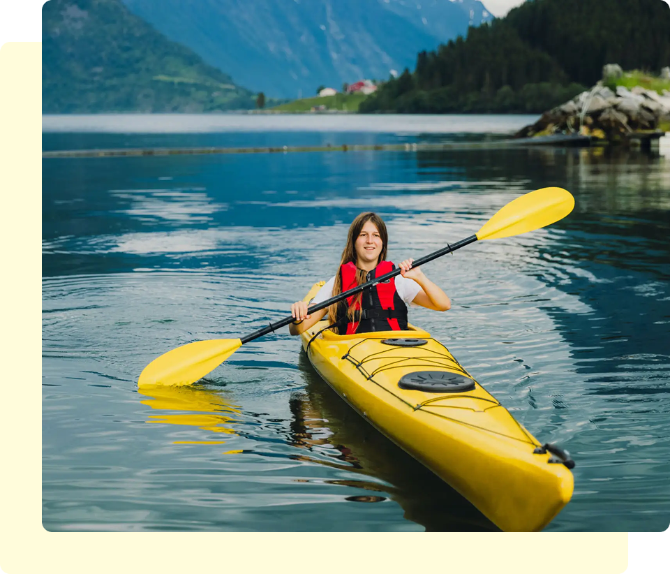 Woman kayaking on a calm mountain lake.