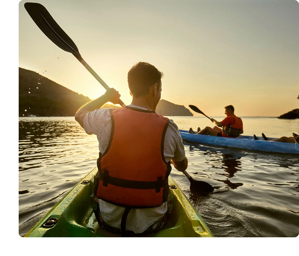 Kayakers paddling on a lake at sunset.