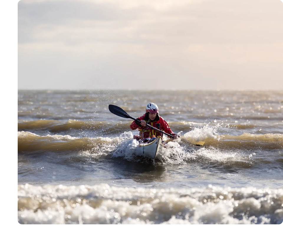 Person kayaking on rough sea waves.
