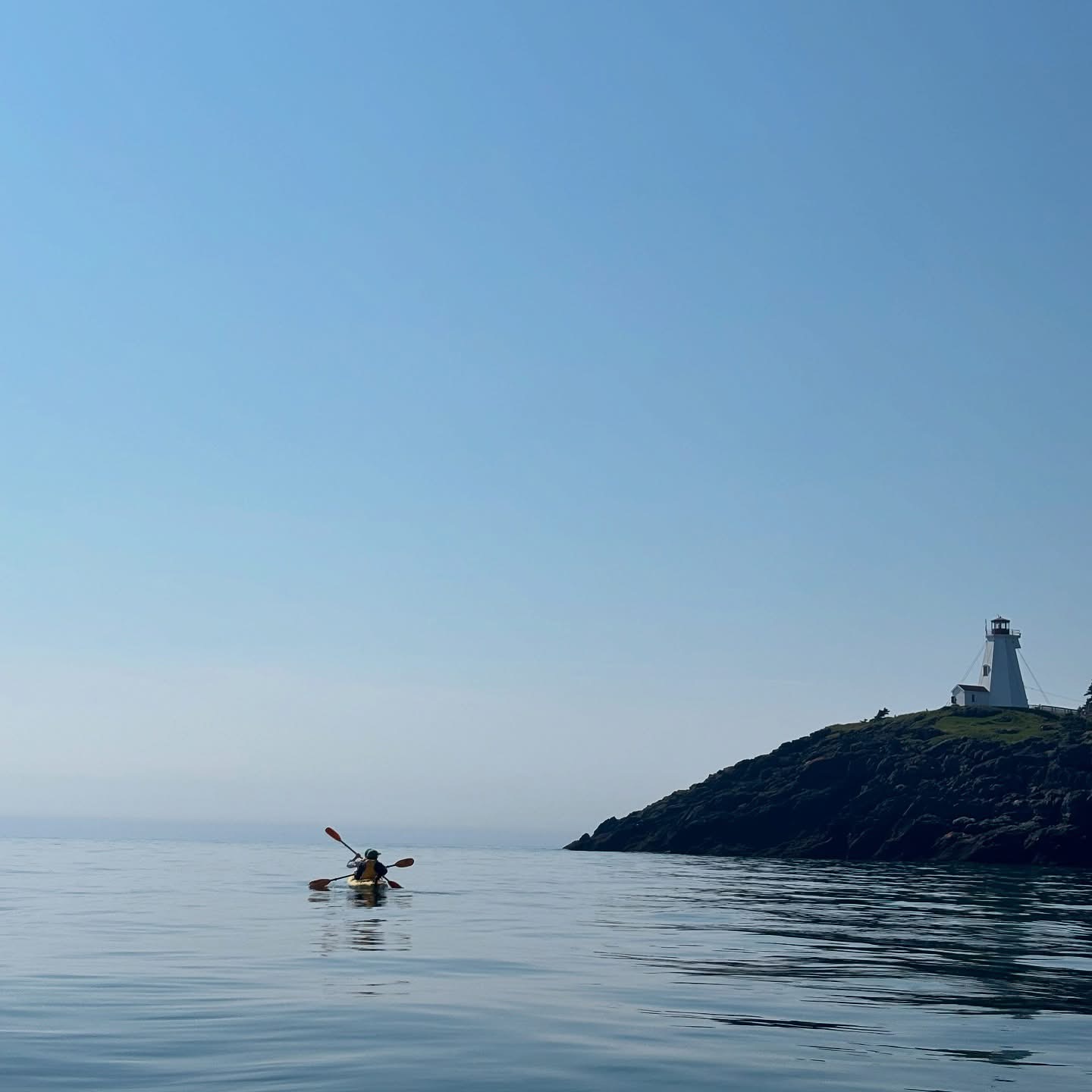 Kayaker near lighthouse on calm water