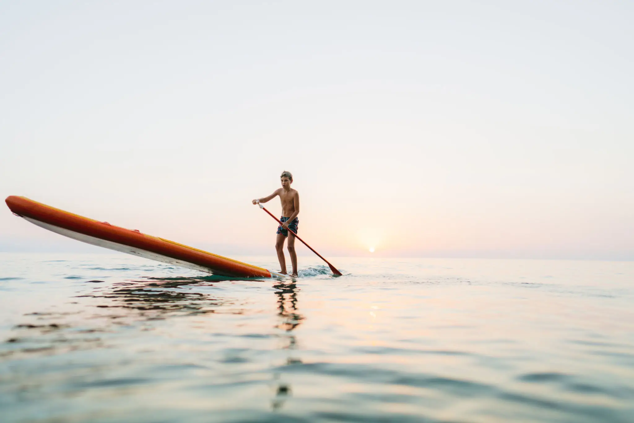 Person paddleboarding on calm ocean water.