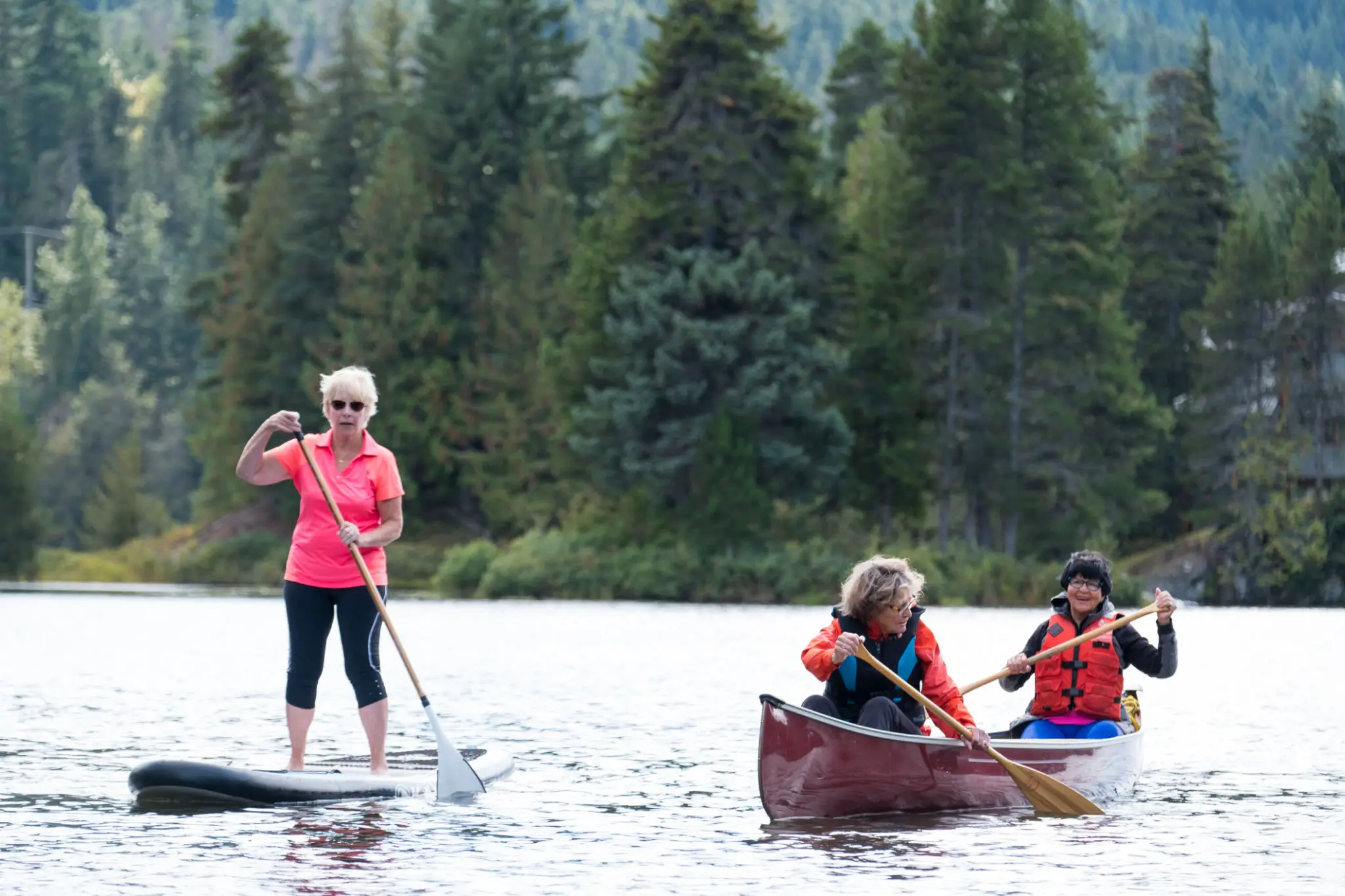 People paddleboarding and canoeing on a lake.