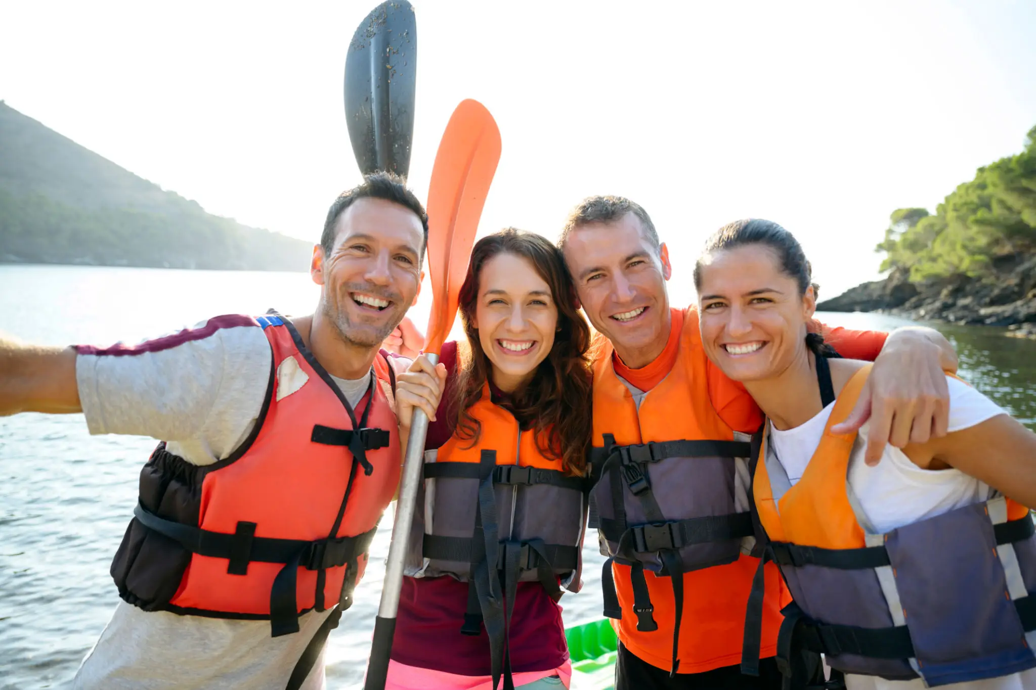 Group of friends kayaking in life vests.