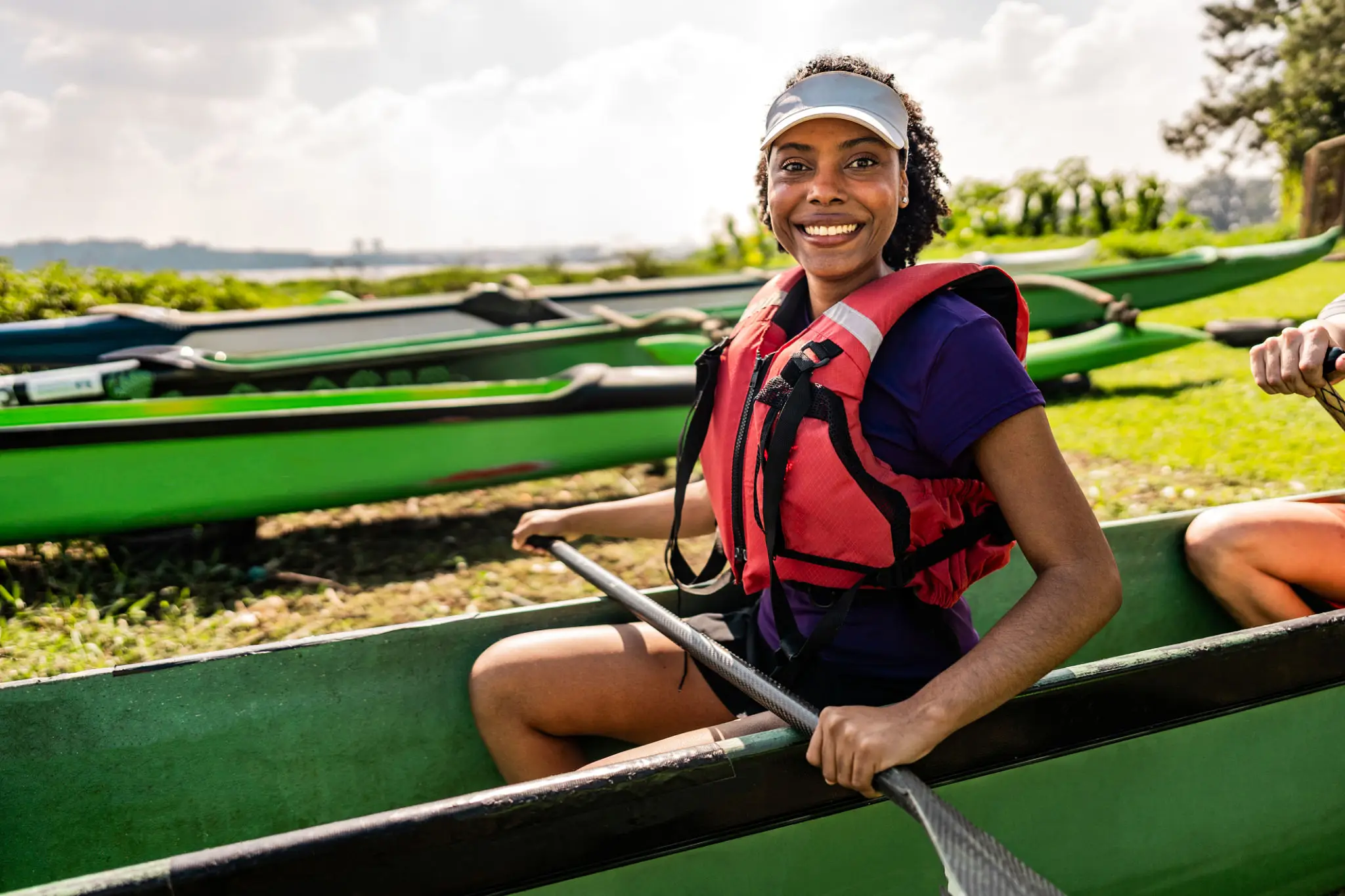 Smiling person in kayak wearing life jacket.
