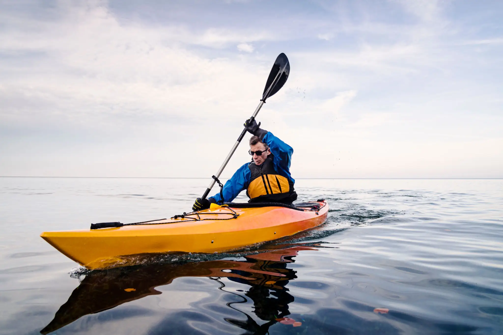 Person kayaking on calm open water.
