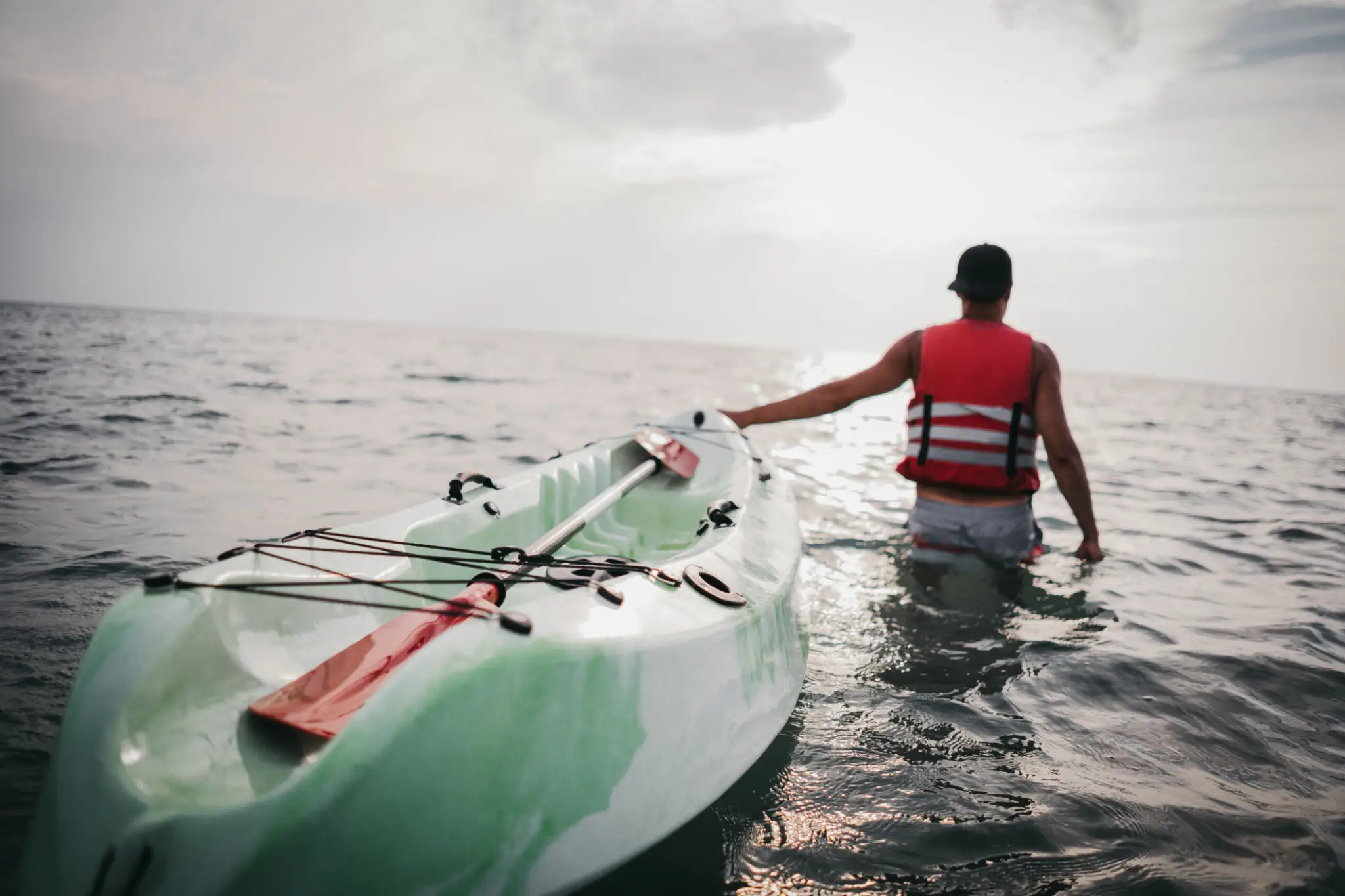 Person pulling kayak in the ocean.