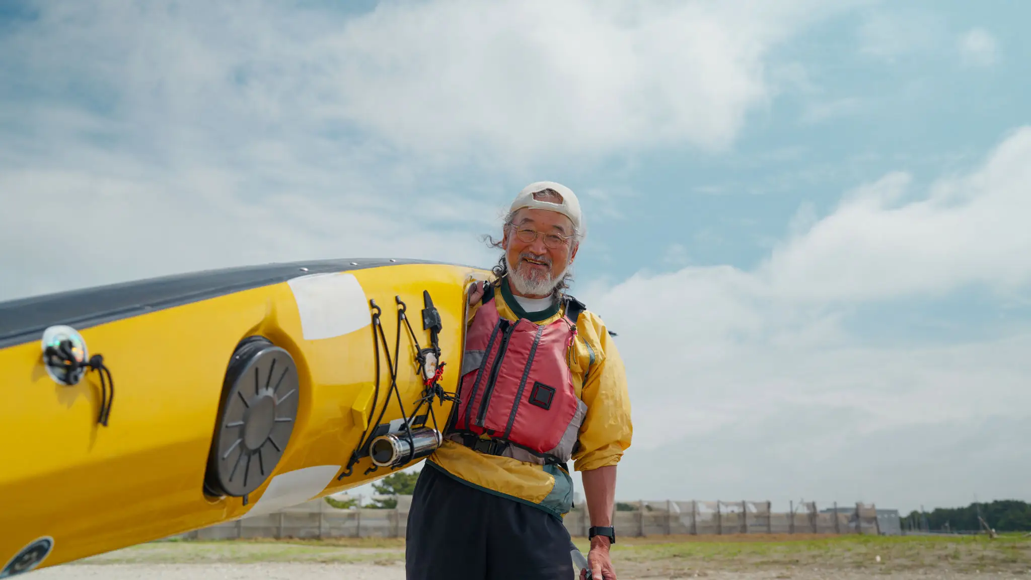 Man smiling while holding a yellow kayak.
