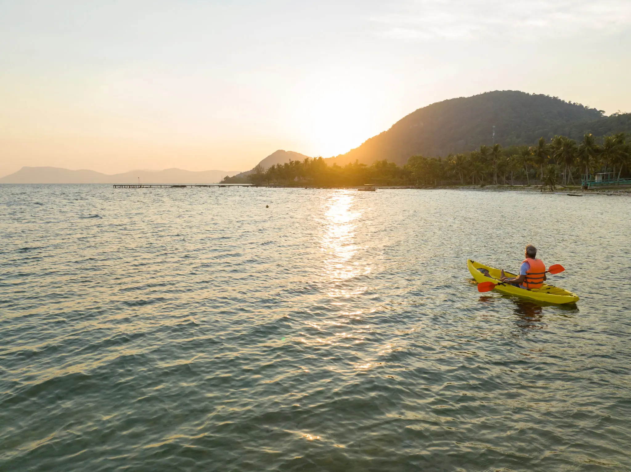 Person kayaking at sunset on the ocean.