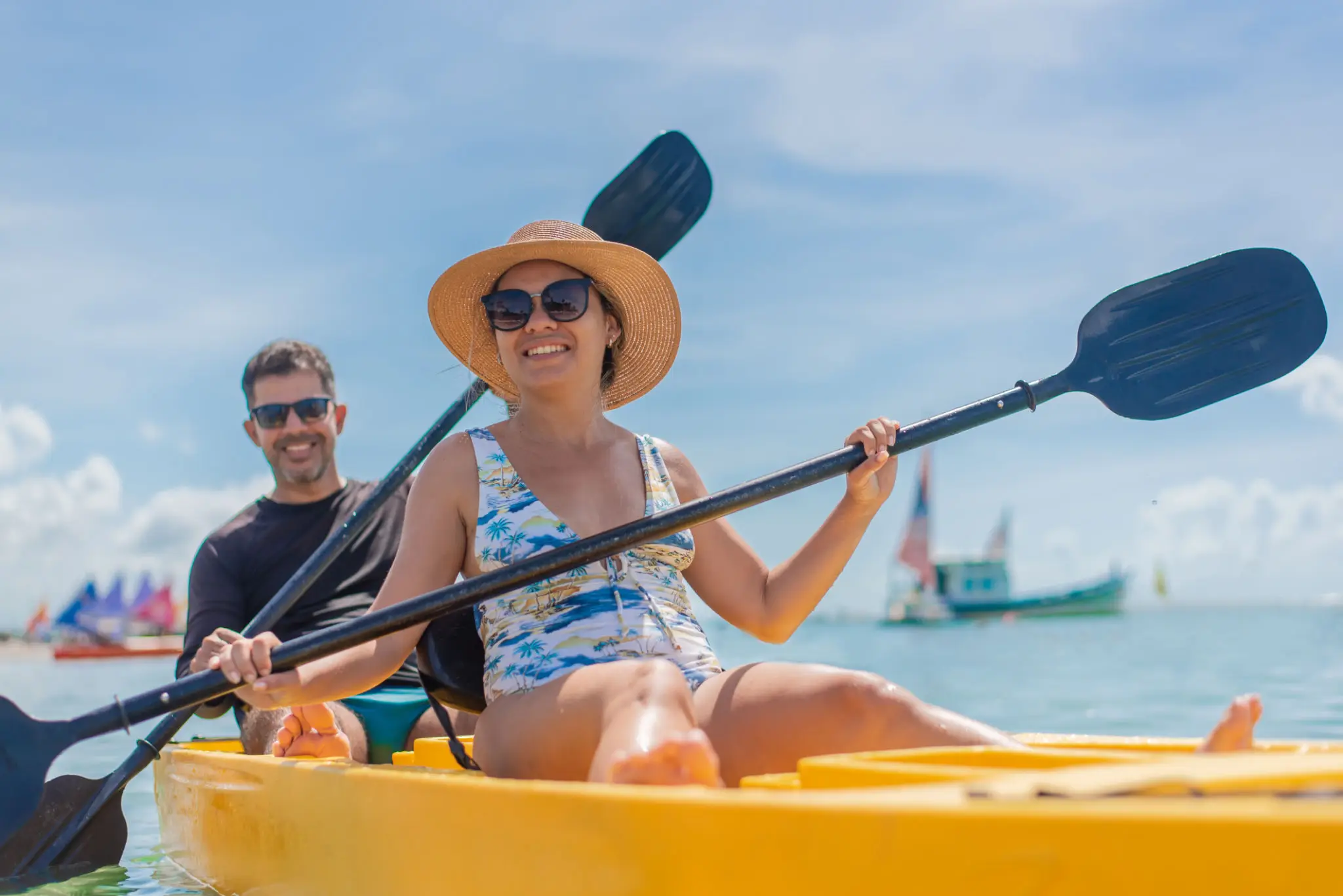 Couple kayaking in sunny, tropical waters.